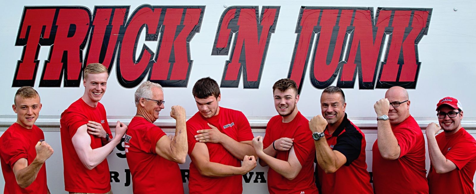 Truck N Junk team members flexing in front of truck